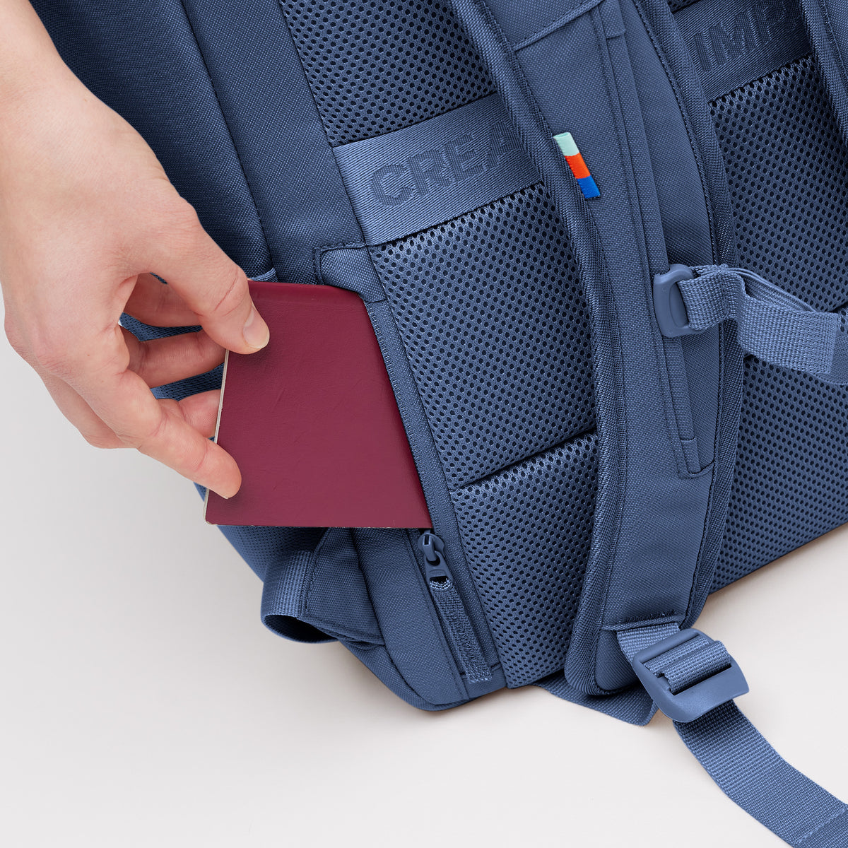 PRO PACK Rucksack mit Hand, die einen Reisepass in ein verstecktes Fach auf der Rückseite steckt.