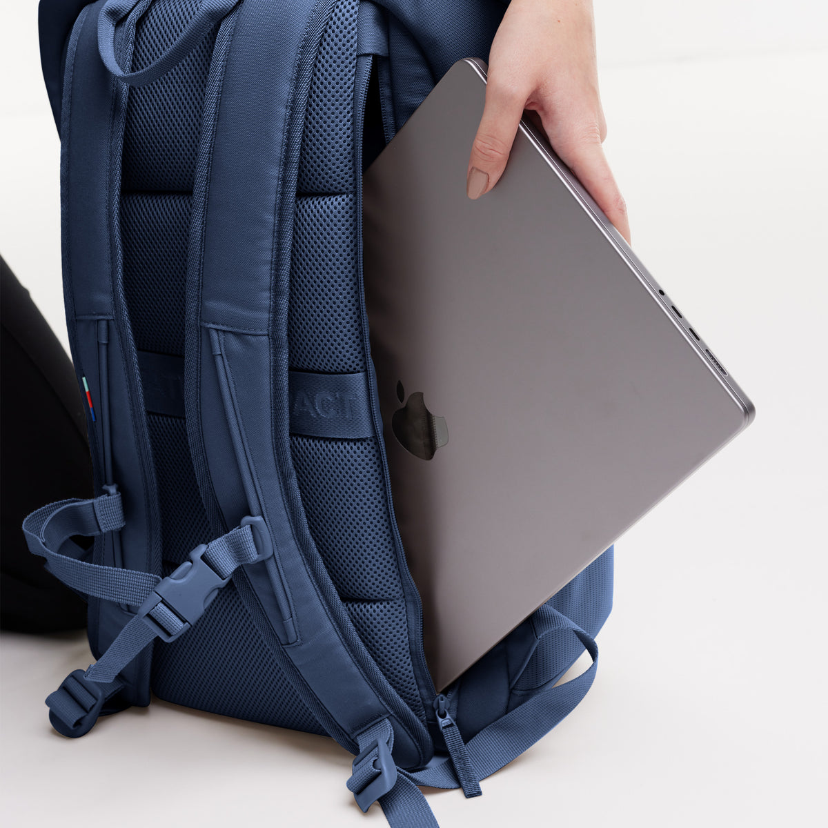 PRO PACK Rucksack, Detailaufnahme: Eine Frau steckt einen Laptop in das gepolsterte Rückenfach.