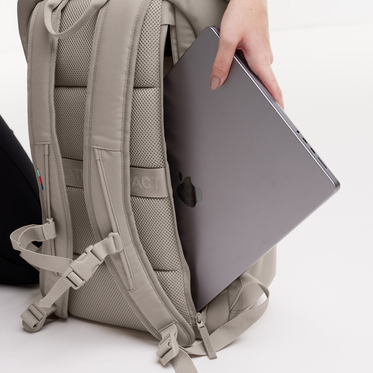 PRO PACK Rucksack in scallop (helles Beige), eine Frau steckt ein Laptop in das gepolsterte Rückfach.