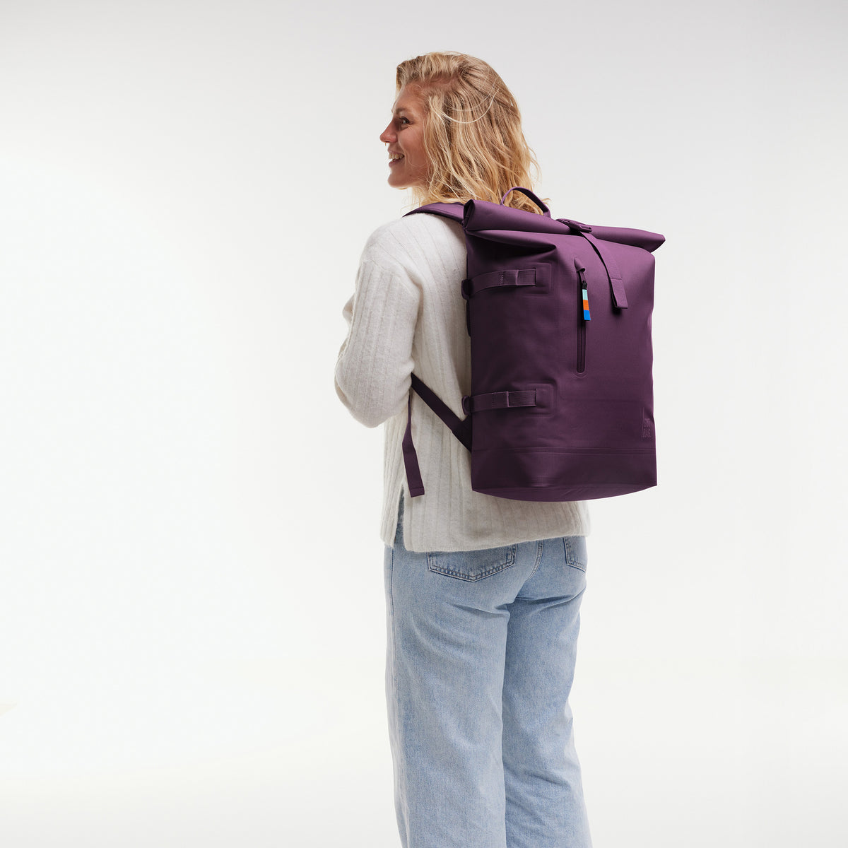 ROLLTOP Rucksack in favia (warmes Dunkellila / Pflaumenfarben) von einer Frau als Rucksack auf dem Rücken getragen.
