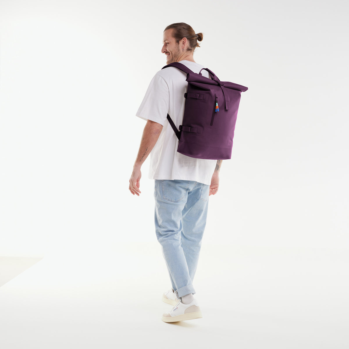ROLLTOP 2.0 Rucksack in favia (warmes Dunkellila / Pflaumenfarben) von einem Mann auf dem Rücken getragen.