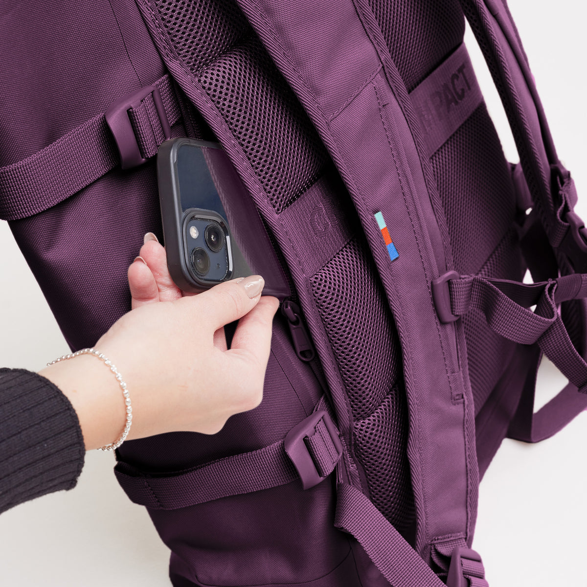 Detailaufnahme eines ROLLTOP 2.0 Rucksacks in favia (warmes Dunkellila / Pflaumenfarben), der von einer Frau bedient wird.