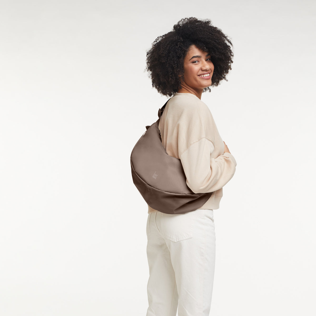 MOON BAG LARGE Tasche in oyster (klassisches Taupe-Braun) von einer Frau crossbody getragen.