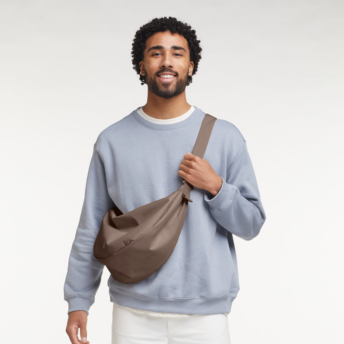 MOON BAG LARGE Tasche in oyster (klassisches Taupe-Braun) von einem Mann crossbody getragen.
