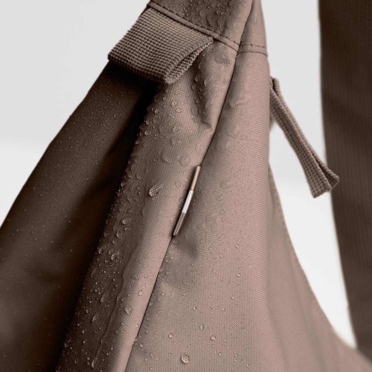 MOON BAG LARGE Tasche in oyster (klassisches Taupe-Braun), Detailaufnahme mit Wassertropfen auf wasserabweisendem Material.