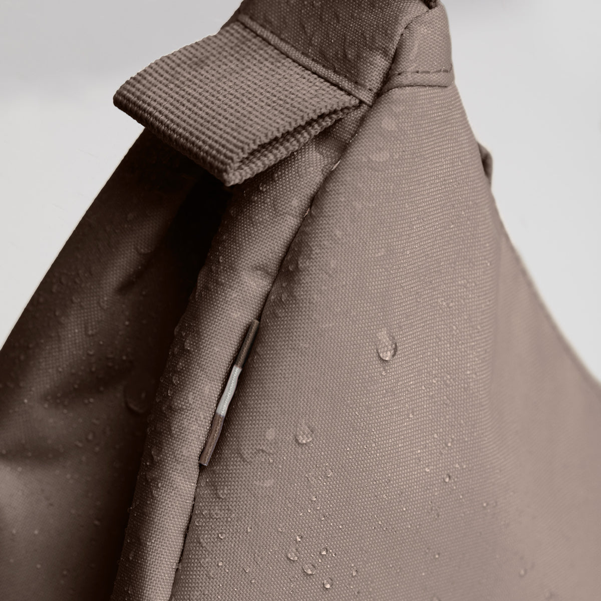 MOON BAG SMALL Tasche in oyster (klassisches Taupe-Braun) als Detailaufnahme mit Wassertropfen.