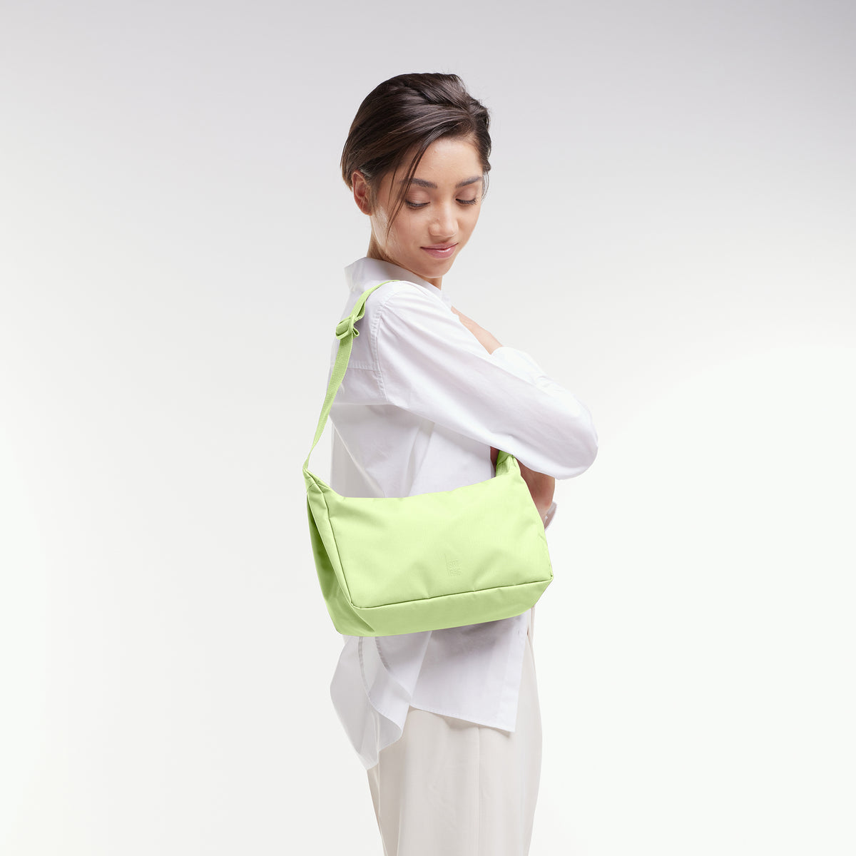 SQUARE BAG SMALL Tasche in wrasse (neonfarbenes Hellgrün) von einer Frau über der Schulter getragen.