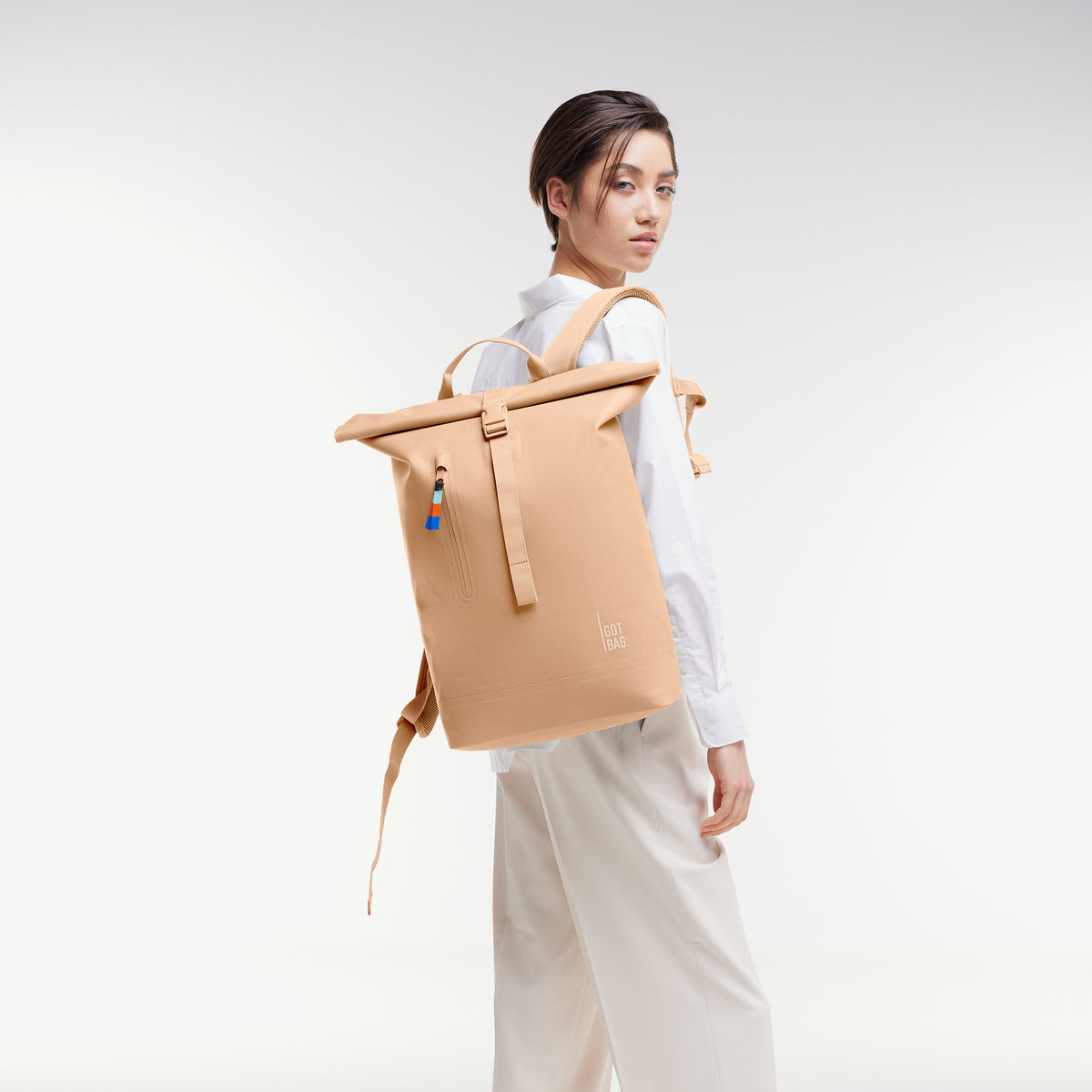ROLLTOP LITE 2.0 Rucksack in krill (frischer pastellfarbener Pfirsichton) von einer Frau als Rucksack auf dem Rücken getragen.