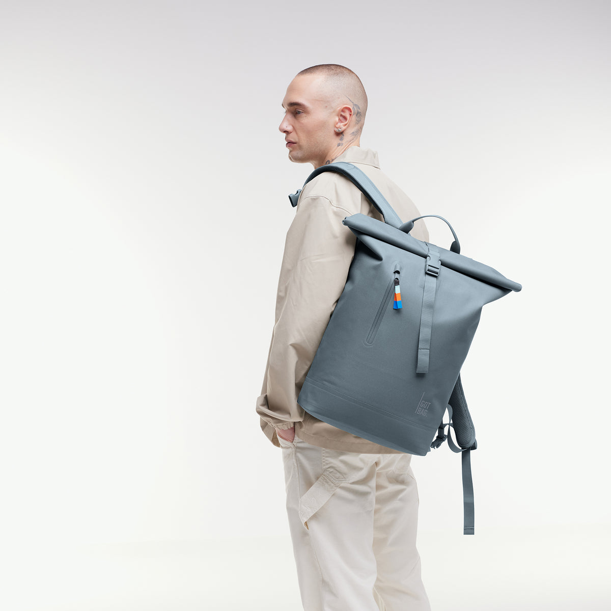 ROLLTOP LITE Rucksack in marlin (grau-blau) von einem Mann auf dem Rücken getragen.