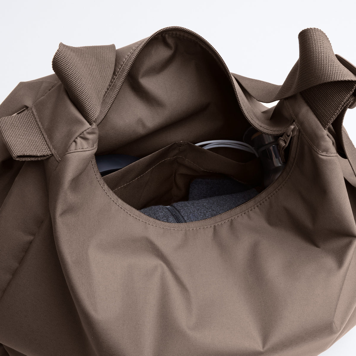 CURVED BAG Tasche in oyster (klassisches Taupe-Braun) als Detailaufnahme des geöffneten Innenraums mit Fächern und Reißverschluss.