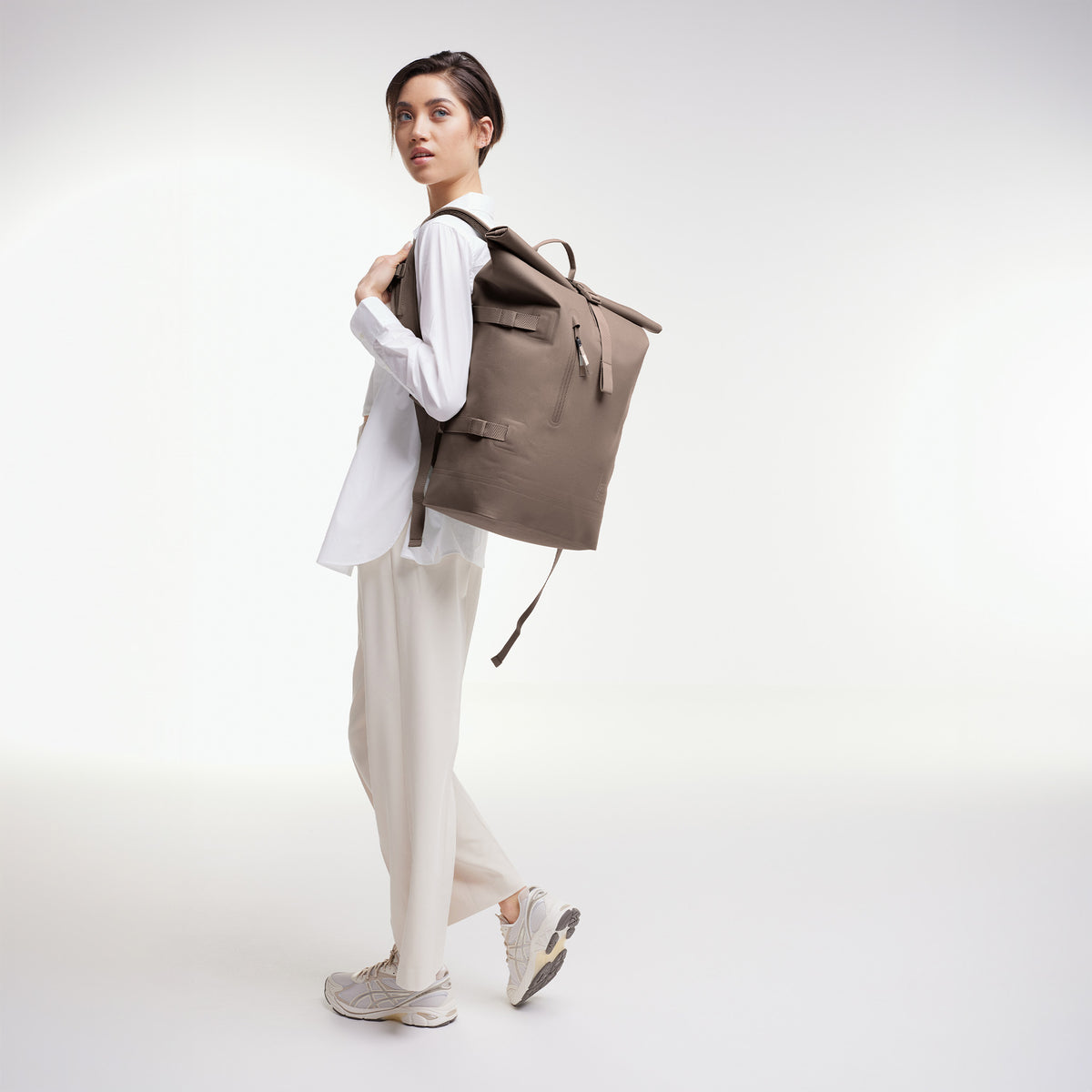 ROLLTOP 2.0 Rucksack in oyster (klassisches Taupe-Braun) von einer Frau auf dem Rücken getragen.