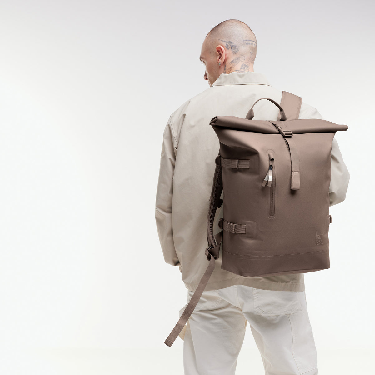 ROLLTOP Rucksack in oyster (klassisches Taupe-Braun) von einem Mann als Rucksack auf dem Rücken getragen.