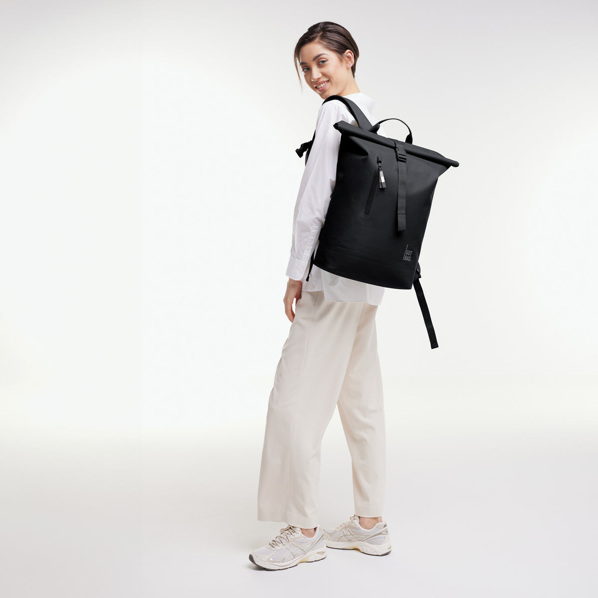 ROLLTOP LITE Rucksack in black (Schwarz) von einer Frau als Rucksack auf dem Rücken getragen.