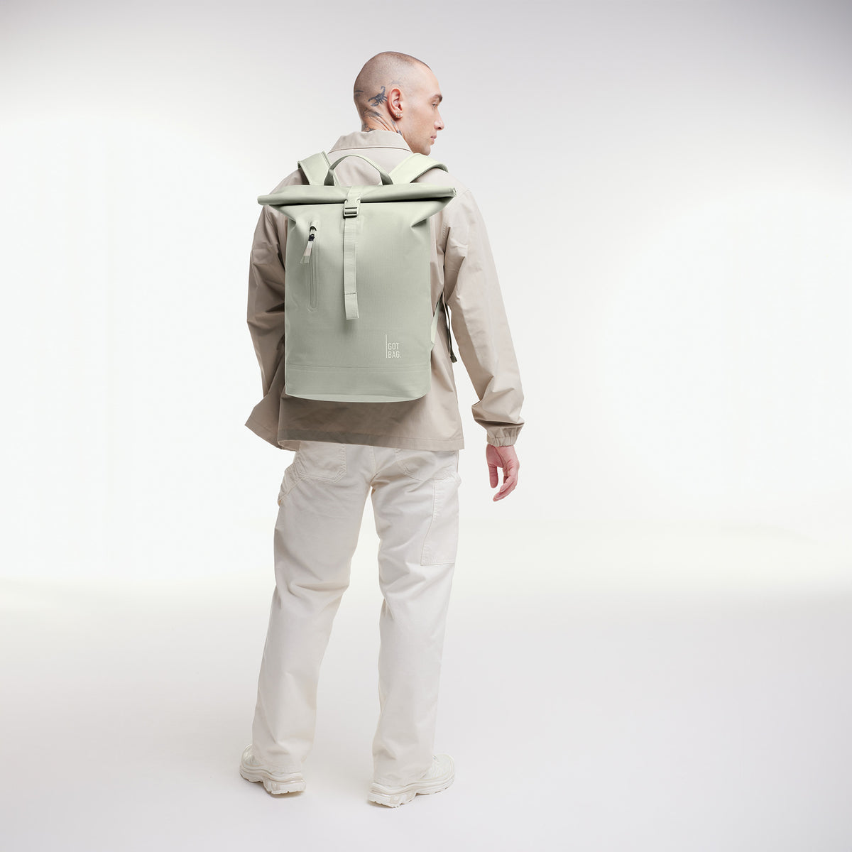 ROLLTOP LITE 2.0 MONOCHROME Rucksack in porpoise (helles Grau mit frischem grünen Unterton) von einem Mann als Rucksack auf dem Rücken getragen.