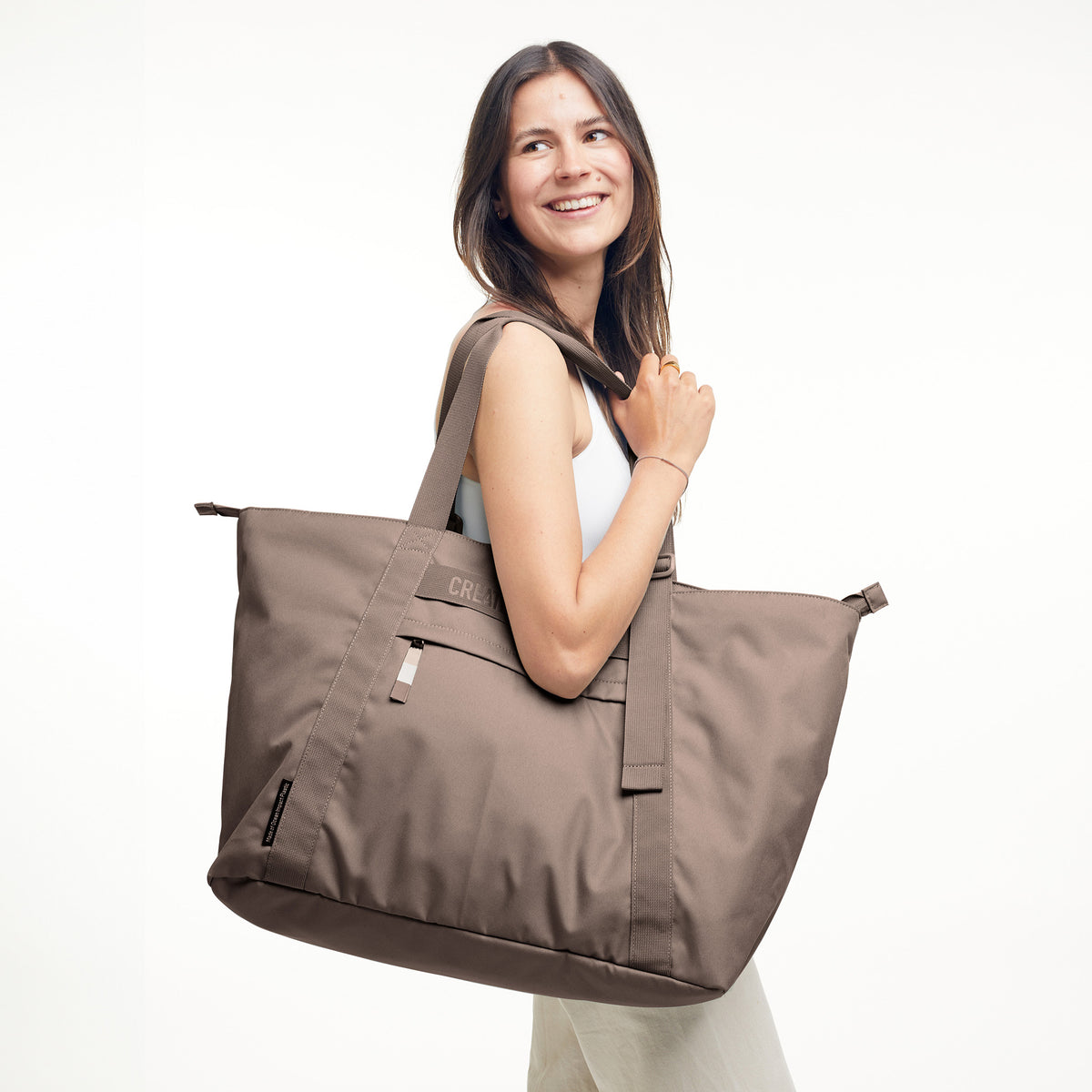 TOTE BAG Tasche in oyster (klassisches Taupe-Braun) von einer Frau über der Schulter getragen.