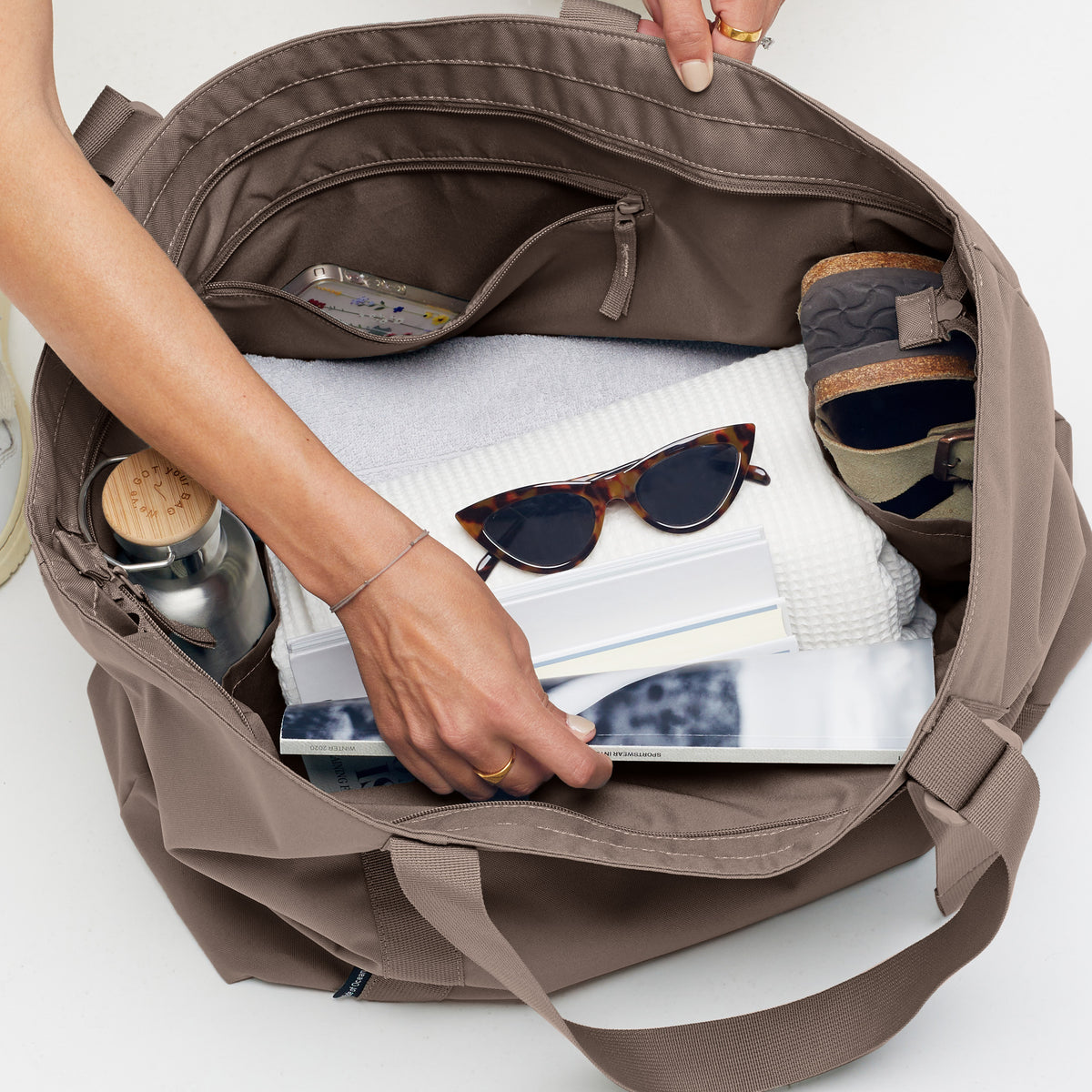 Eine Frau greift in die offene TOTE BAG Tasche in oyster (klassisches Taupe-Braun).