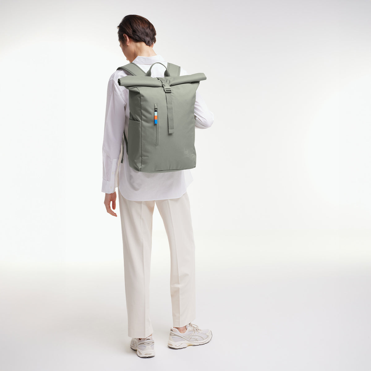 ROLLTOP EASY Rucksack in bass (Salbeigrün) von einer Frau als Rucksack auf dem Rücken getragen.