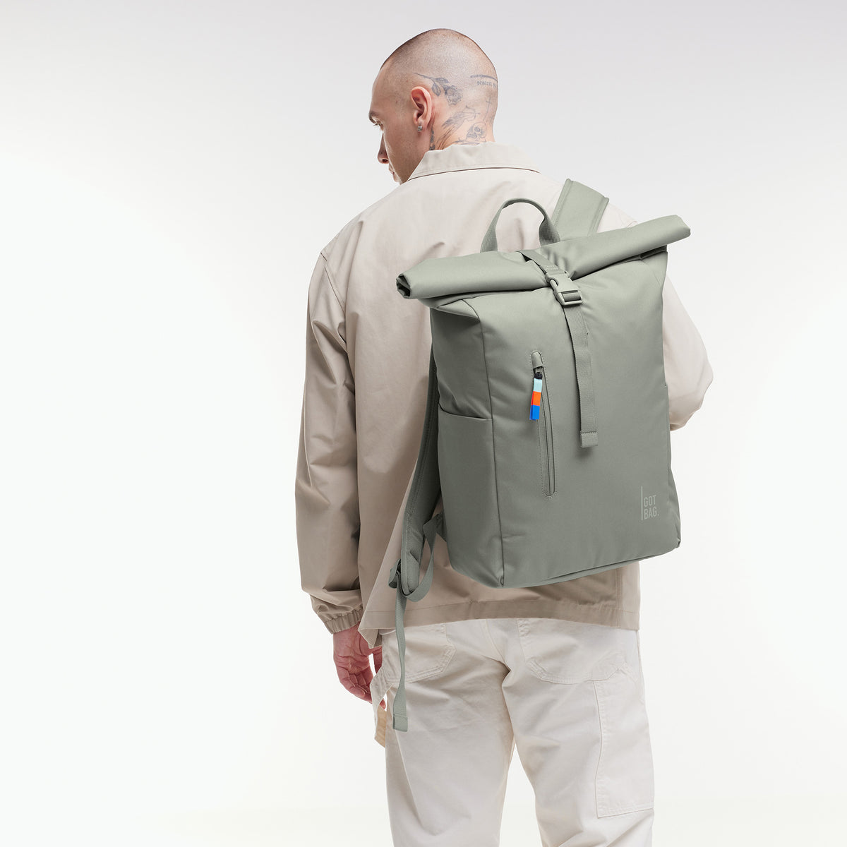 ROLLTOP EASY Rucksack in bass (Salbeigrün) von einem Mann als Rucksack auf dem Rücken getragen.