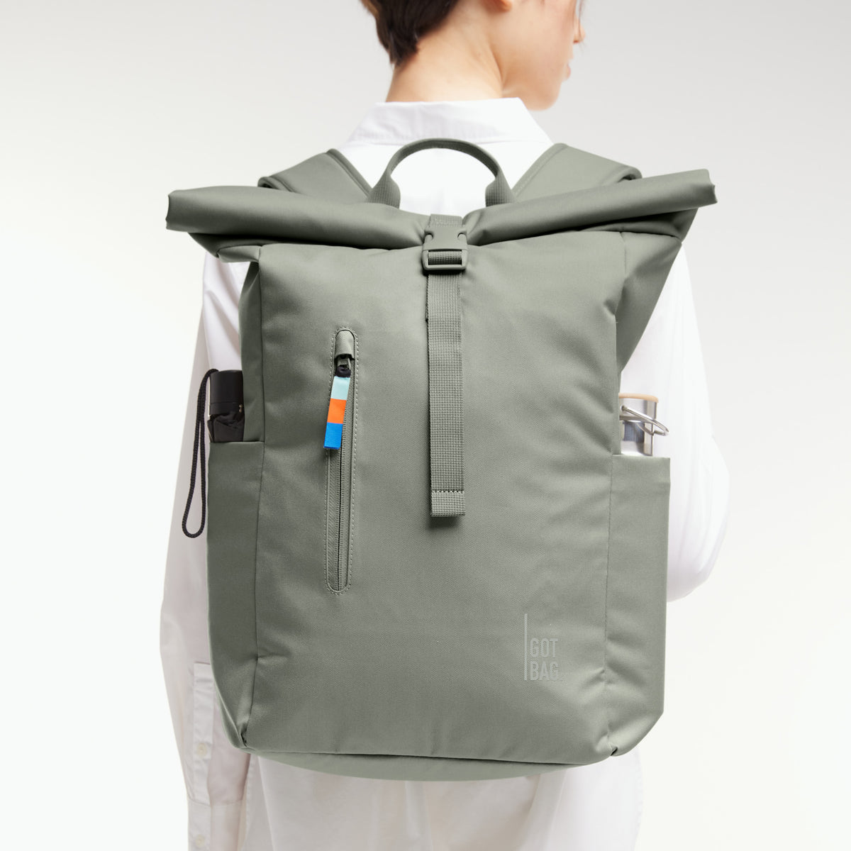 ROLLTOP EASY Rucksack in bass (Salbeigrün) von einer Frau als Rucksack auf dem Rücken getragen.