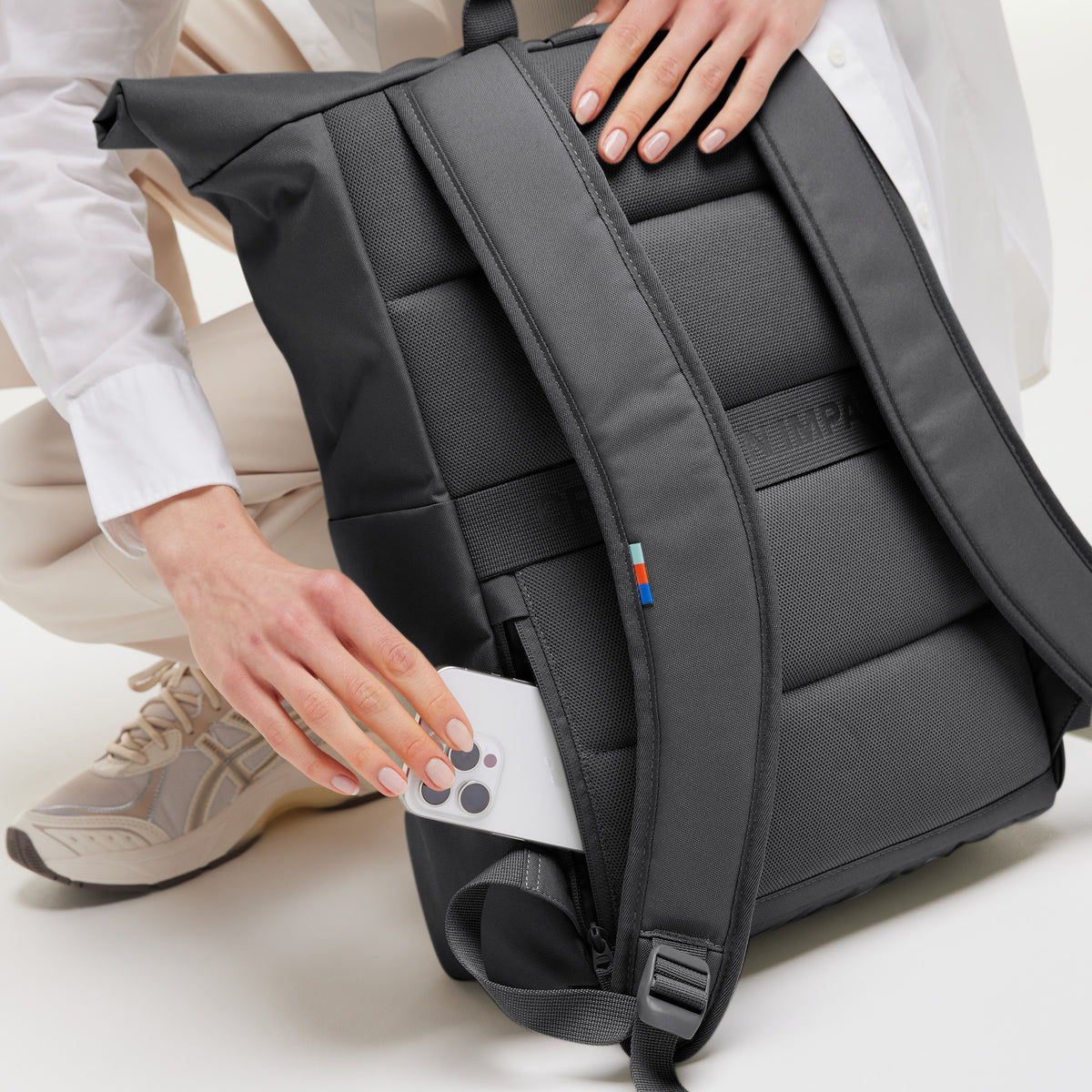 ROLLTOP EASY Rucksack in shark (Dunkelgrau), eine Frau steckt ein Smartphone in die Seitentasche.