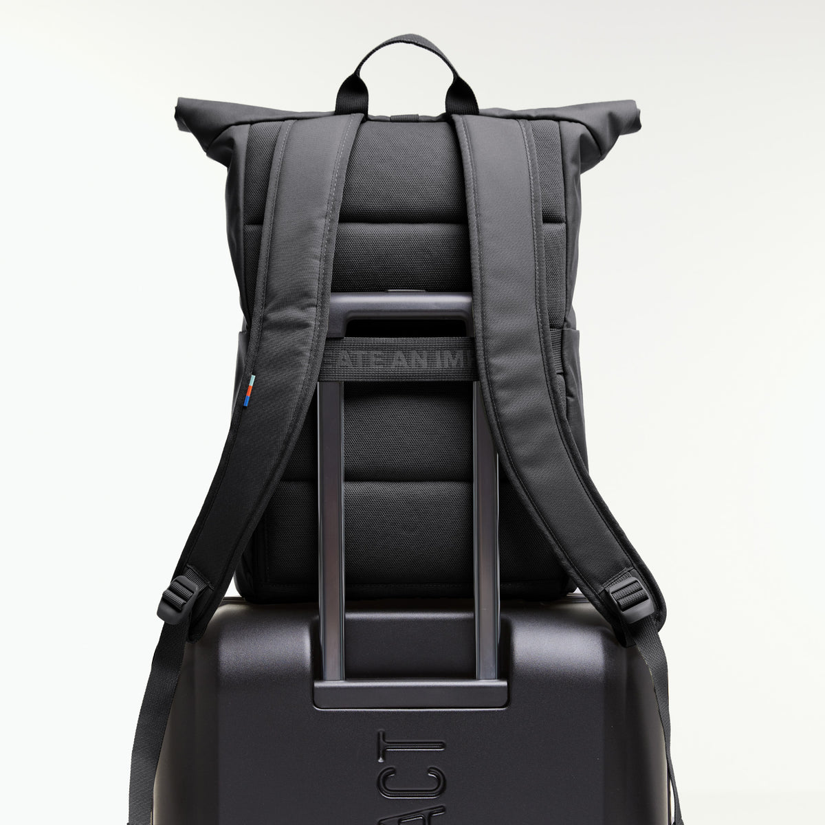 ROLLTOP EASY Rucksack in shark (Dunkelgrau), auf einem Koffer mit herausgezogenem Griff von hinten.