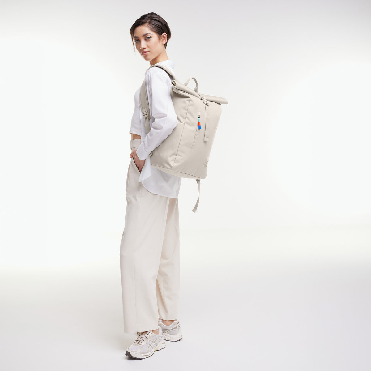 ROLLTOP EASY Rucksack in soft shell (warmes Cremeweiß) von einer Frau als Rucksack auf dem Rücken getragen.