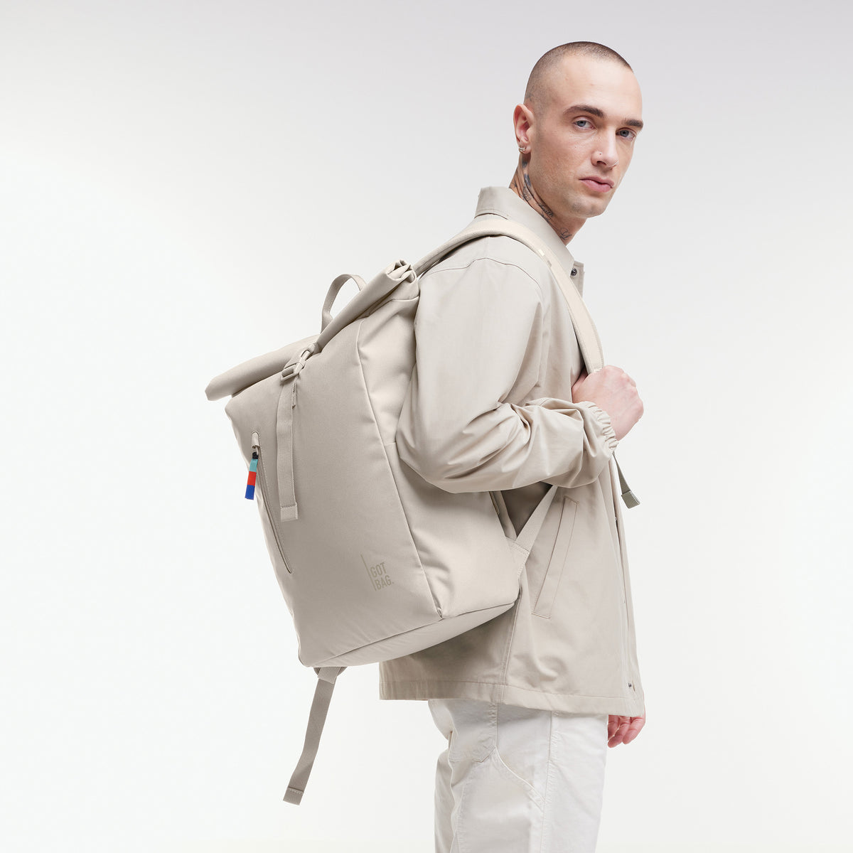 ROLLTOP EASY Rucksack in soft shell (warmes Cremeweiß) von einem Mann über der Schulter getragen.
