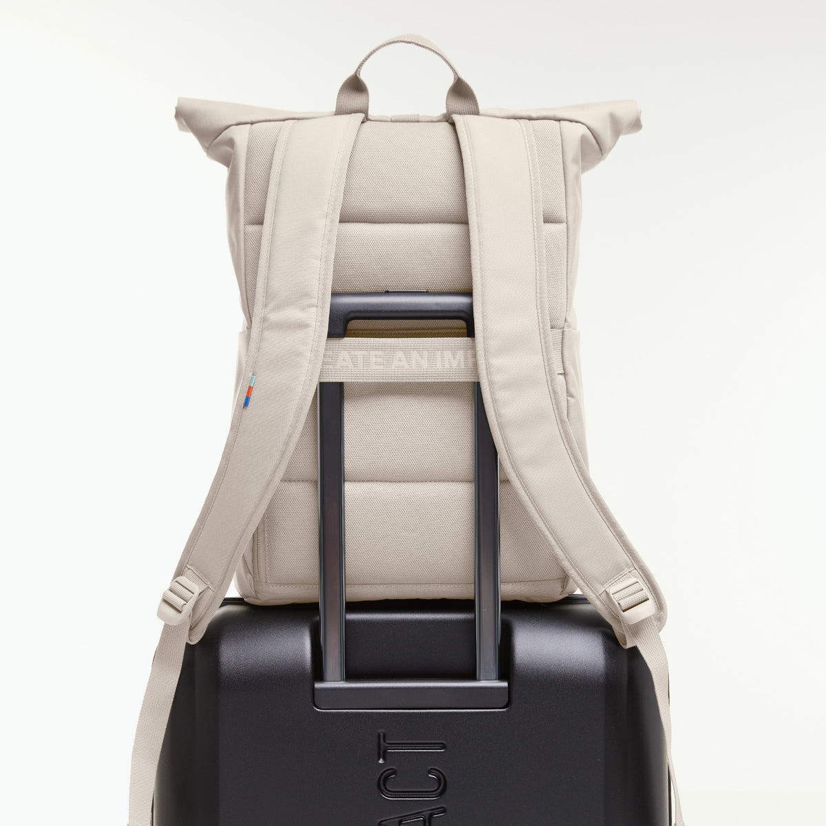 ROLLTOP EASY Rucksack in soft shell (warmes Cremeweiß) auf einem Koffer, am Teleskopgriff befestigt.