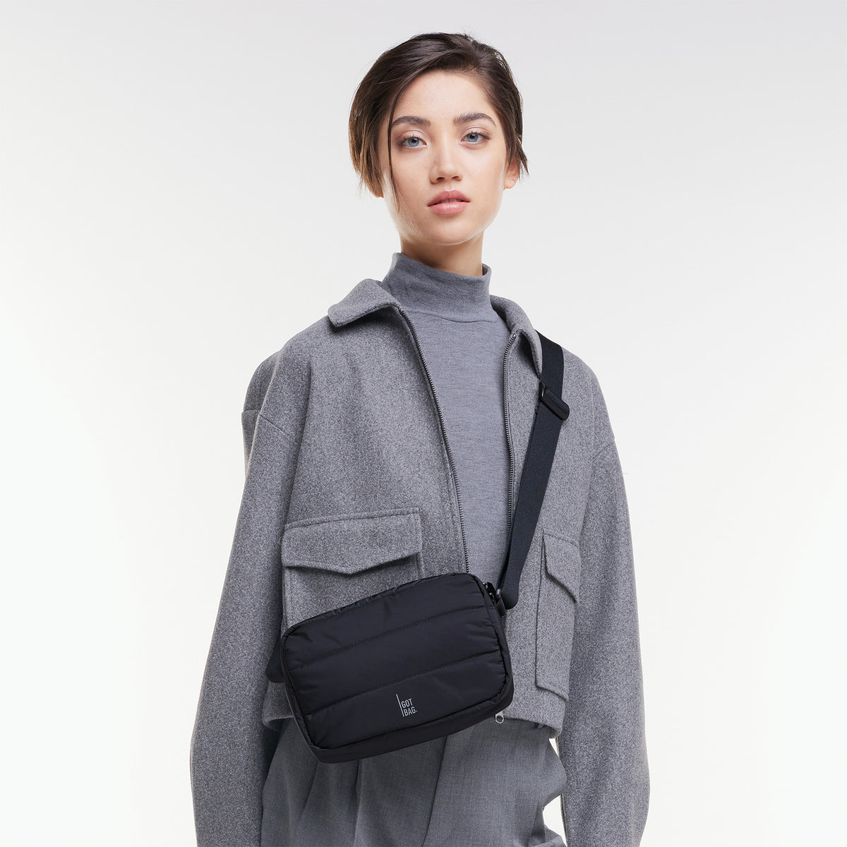 PUFFER CROSSBODY BAG Tasche in black (Schwarz) von einer Frau crossbody getragen.