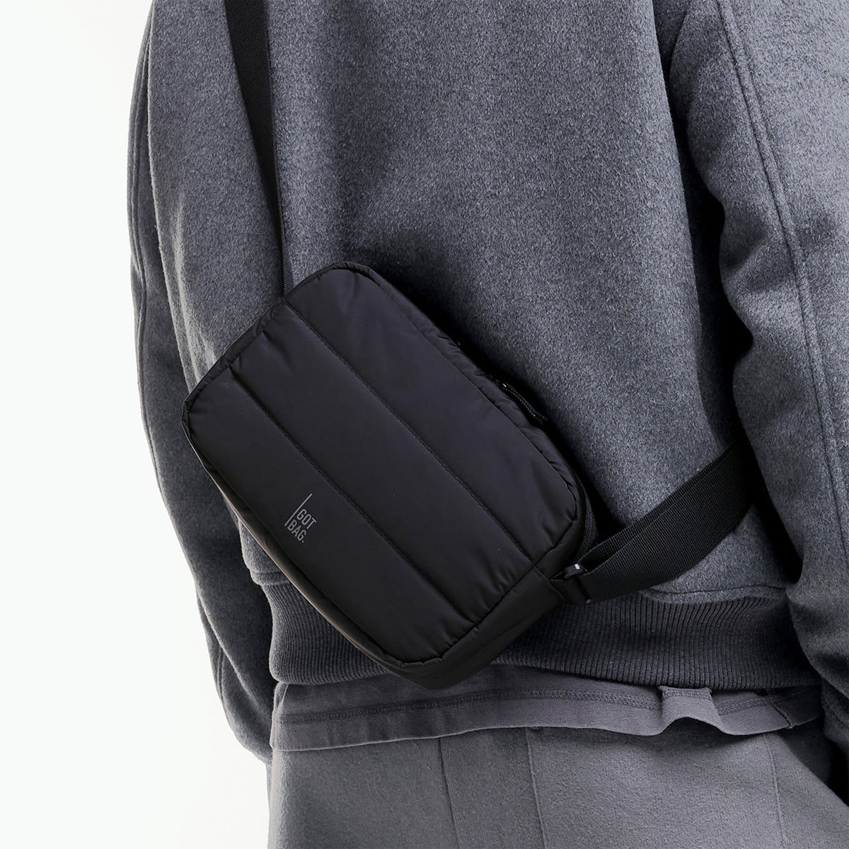 PUFFER CROSSBODY BAG Tasche in black (Schwarz) von einer Person crossbody getragen.