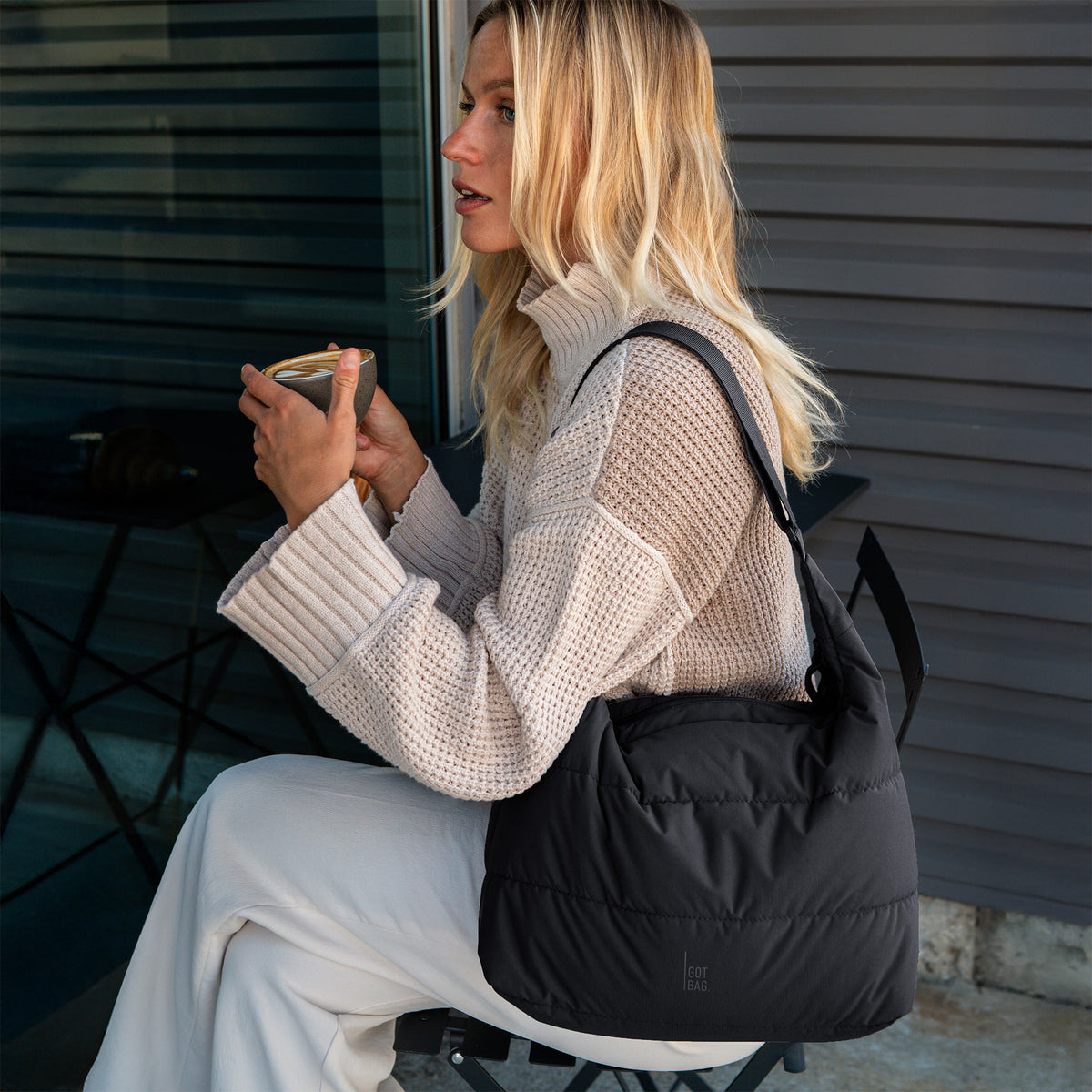 PUFFER SQUARE BAG Tasche in black (Schwarz) von einer Frau über der Schulter getragen.