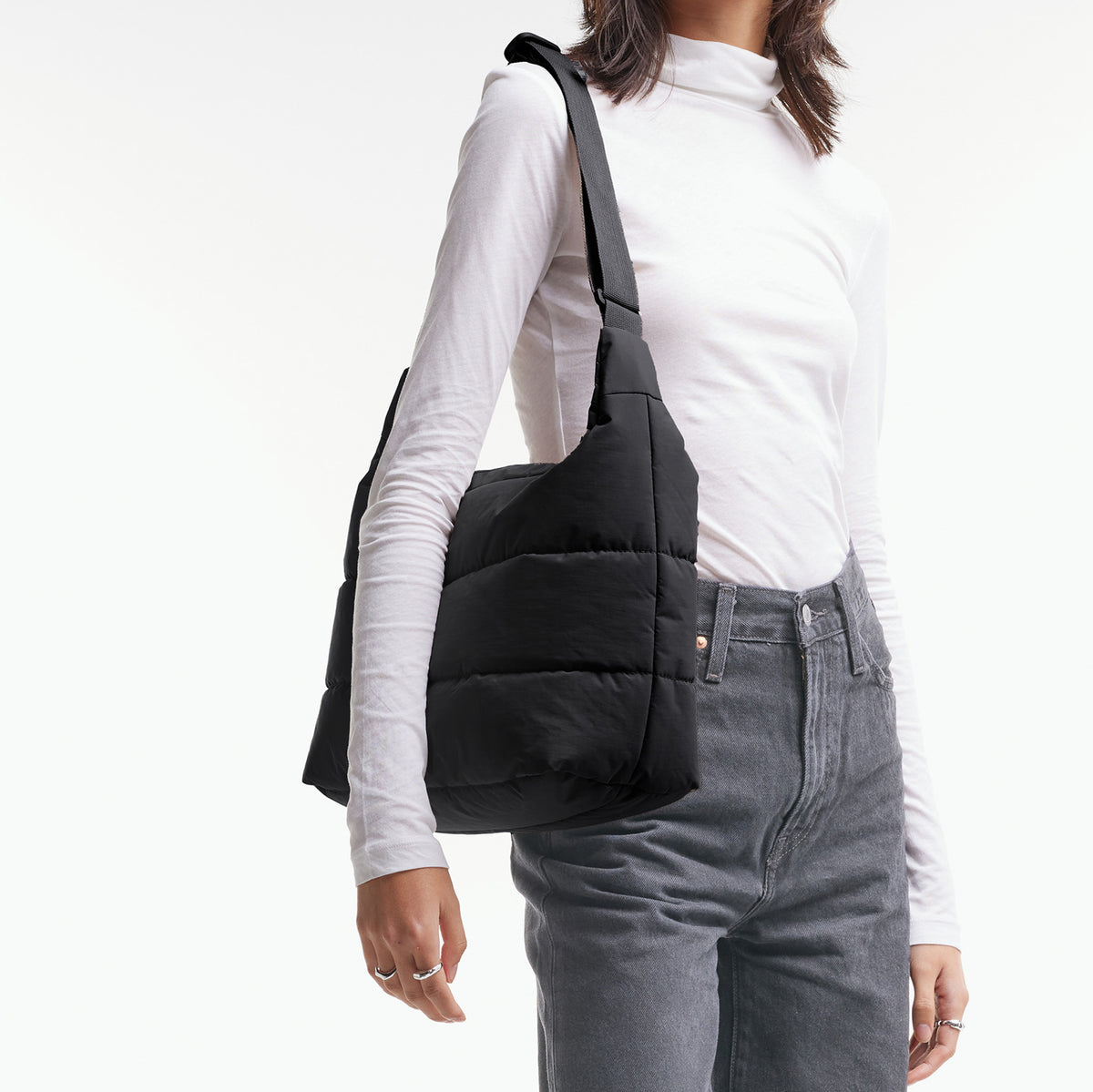 PUFFER SQUARE BAG Tasche in black (Schwarz) von einer Frau über der Schulter getragen.