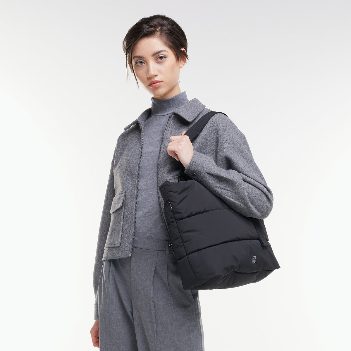 PUFFER TOTE BAG Tasche in black (Schwarz) von einer Frau über der Schulter getragen.