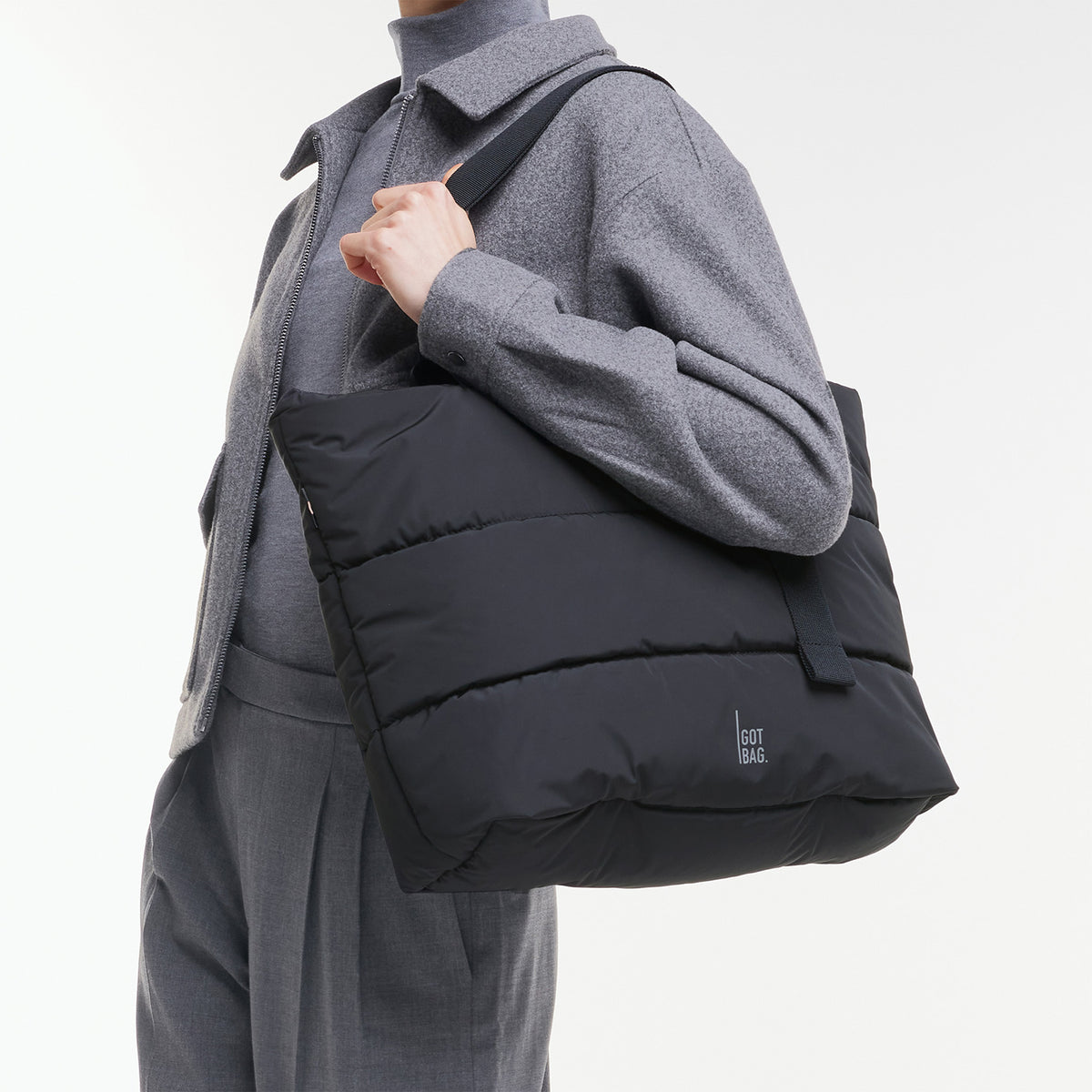 PUFFER TOTE BAG Tasche in black (Schwarz) von einer Frau über der Schulter getragen.