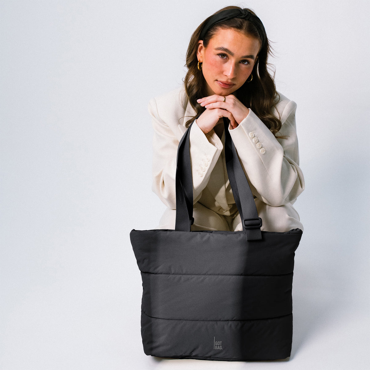PUFFER TOTE BAG Tasche in black (Schwarz) von einer Frau mit den Händen gehalten.