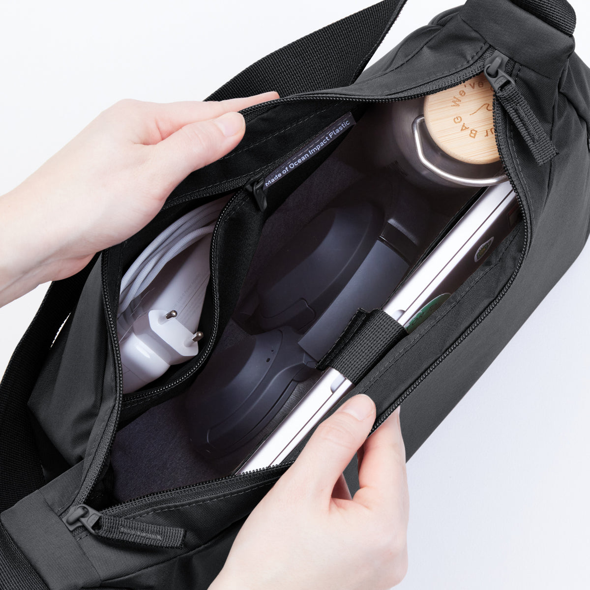 SQUARE BAG LARGE Tasche in black (Schwarz) von einer Frau geöffnet haltend.