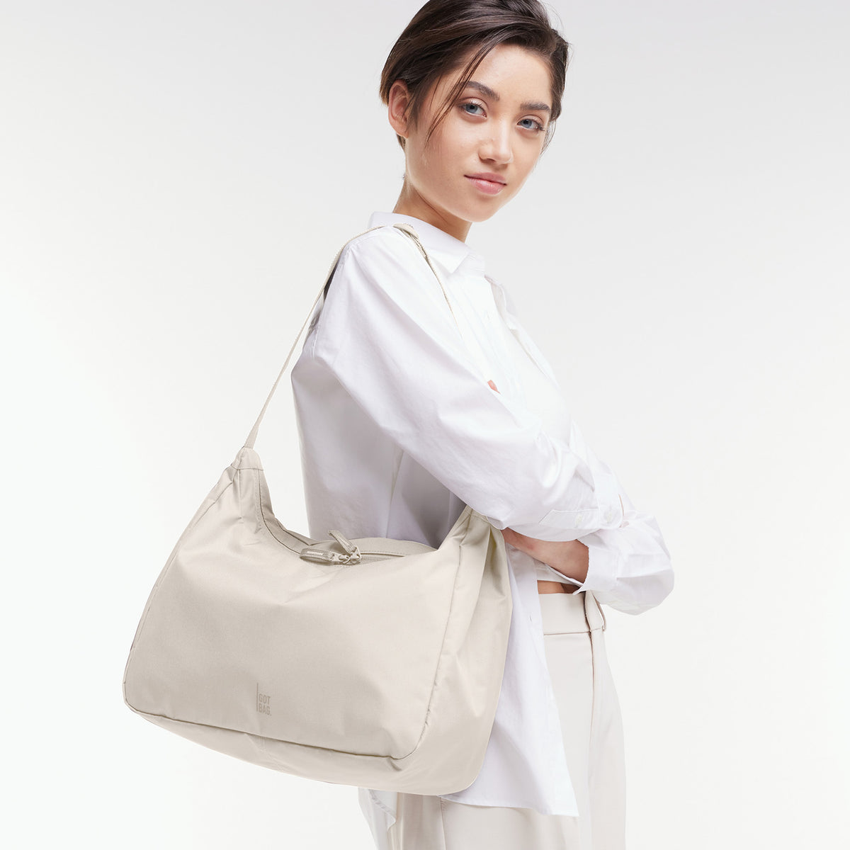 SQUARE BAG LARGE Tasche in soft shell (warmes Cremeweiß) von einer Frau über der Schulter getragen.