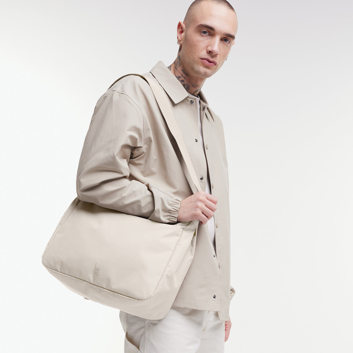 SQUARE BAG LARGE Tasche in soft shell (warmes Cremeweiß) von einem Mann über der Schulter getragen.