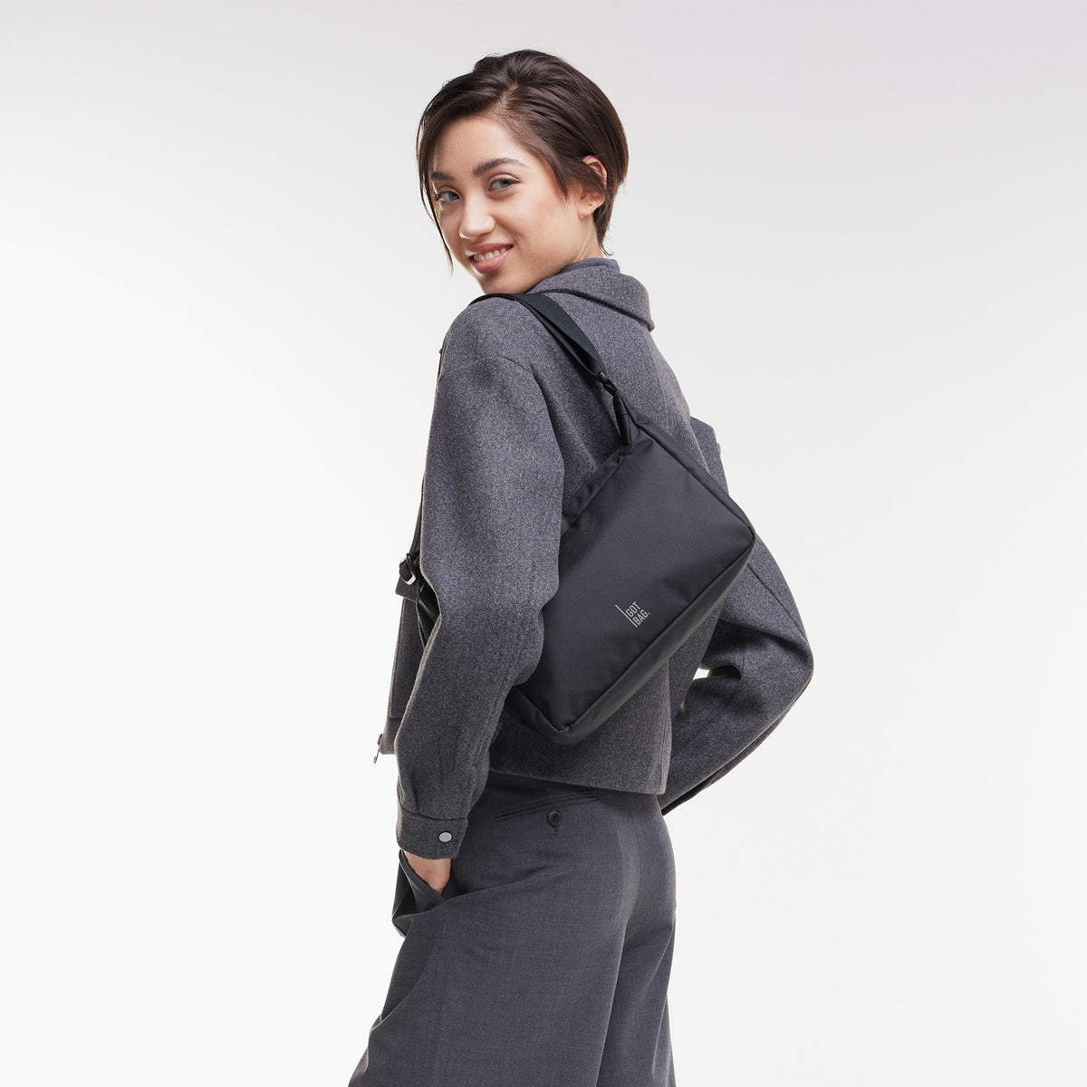 SQUARE BAG SMALL Tasche in black (Schwarz) von einer Frau crossbody getragen.