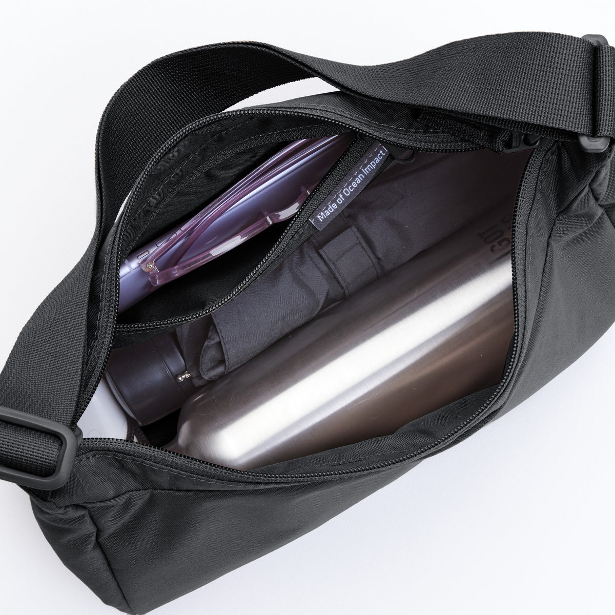 SQUARE BAG SMALL Tasche in black (Schwarz) als Detailaufnahme, gefüllt mit Flaschen und einem Etui.