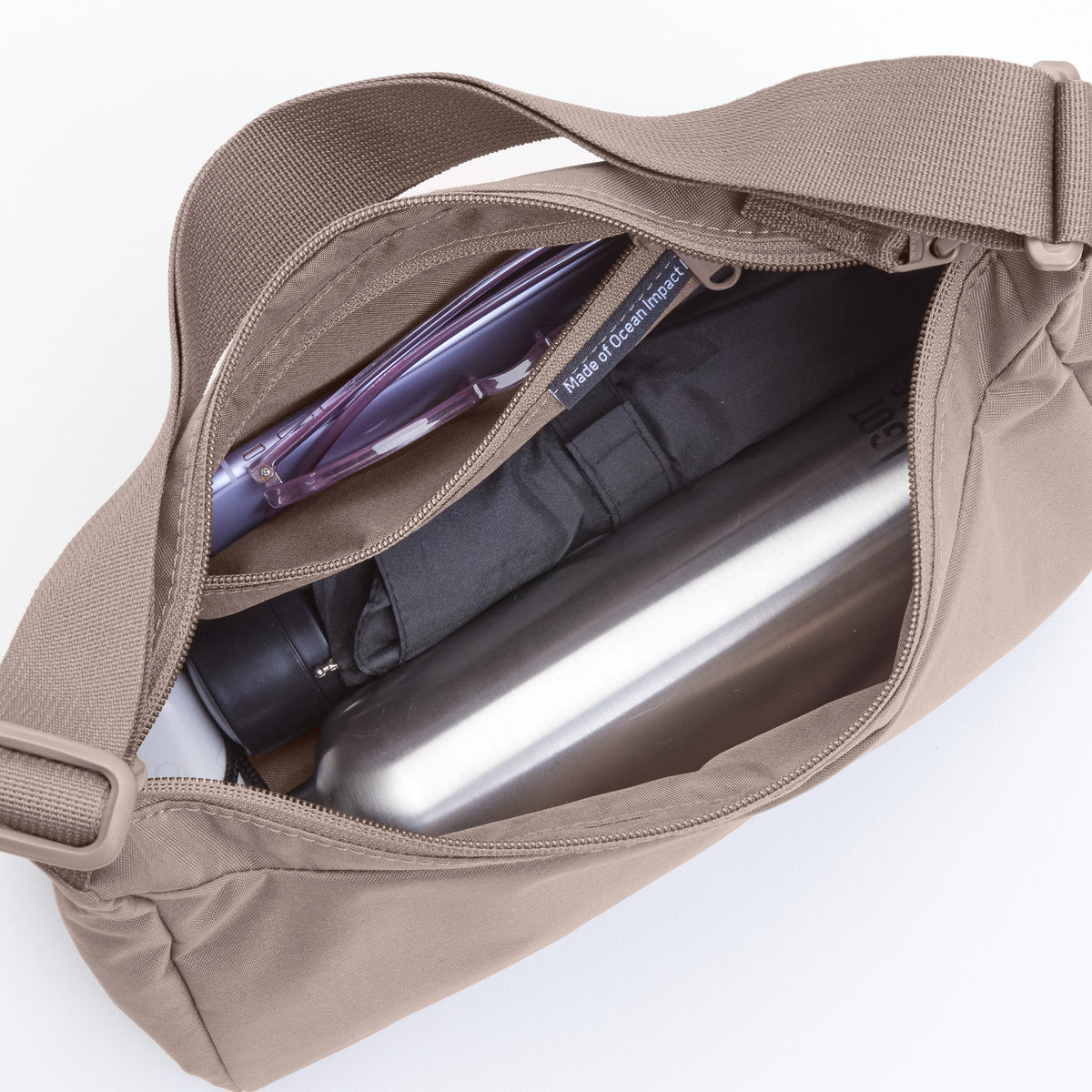SQUARE BAG SMALL Tasche in oyster (klassisches Taupe-Braun), gefüllt mit Wasserflasche, Regenschirm und Brille.