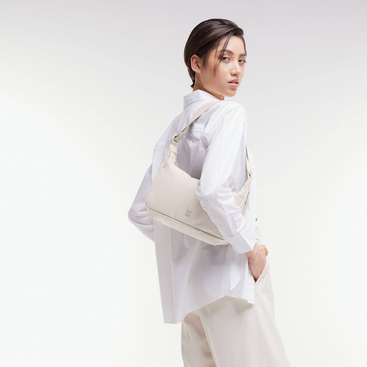 SQUARE BAG SMALL Tasche in soft shell (warmes Cremeweiß) von einer Frau crossbody getragen.