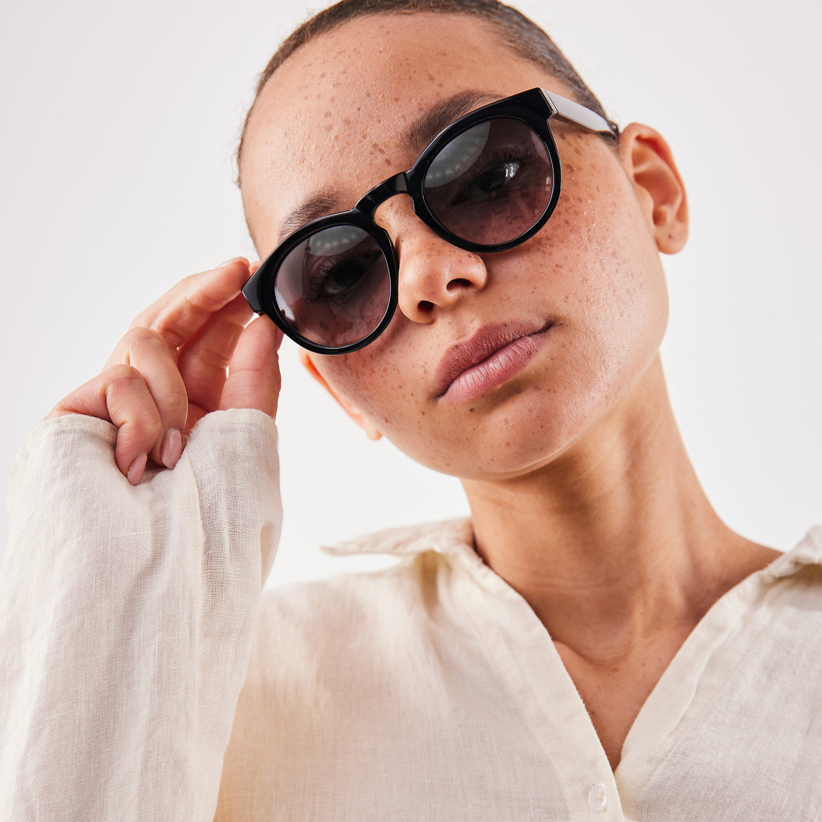 RE SHADES NO.05 RE:SHADE in black (Schwarz) von einer Frau getragen, die sie anpasst.