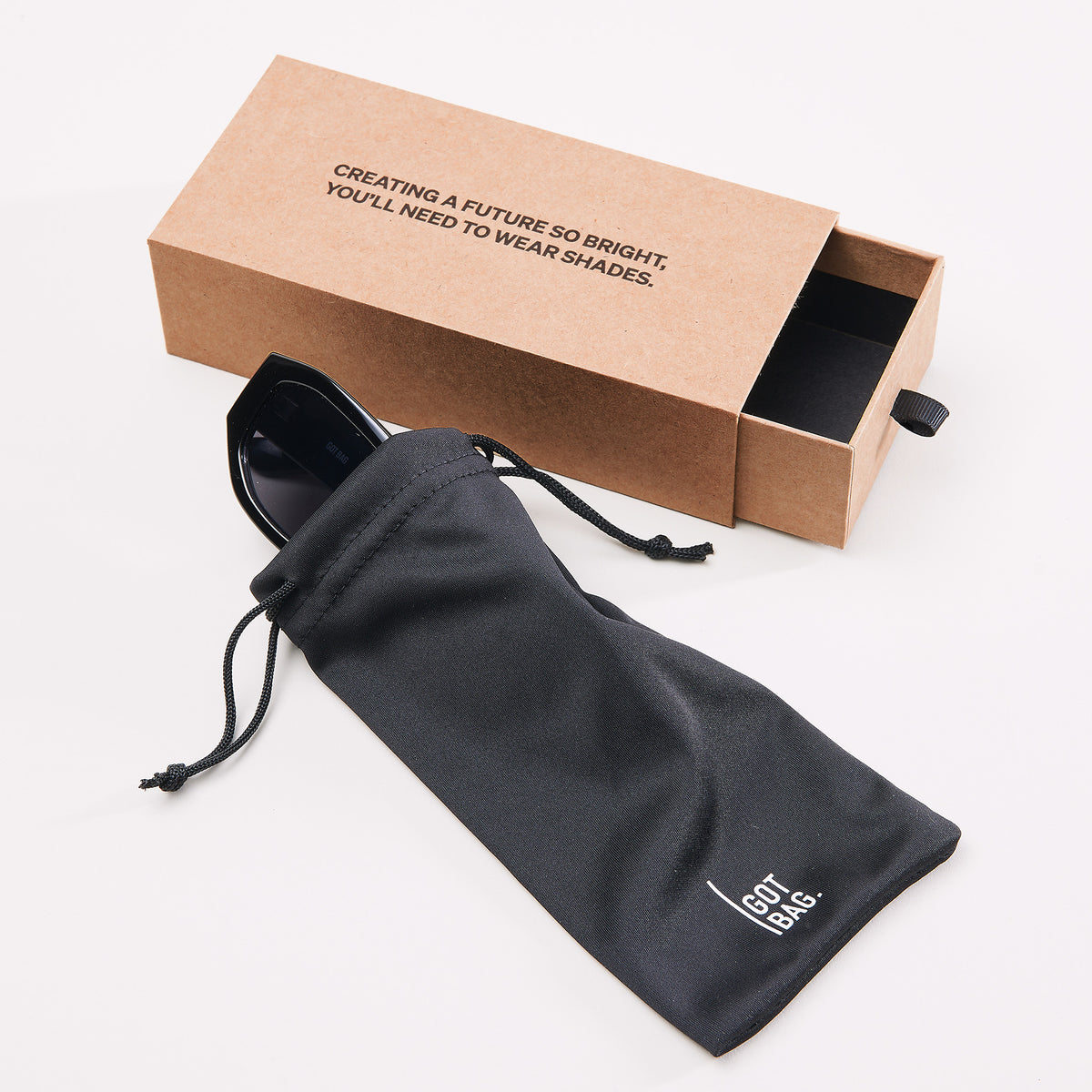 RE SHADES Sonnenbrille, teilweise aus einem Beutel ragend, neben offener Schubladenverpackung mit Schriftzug.