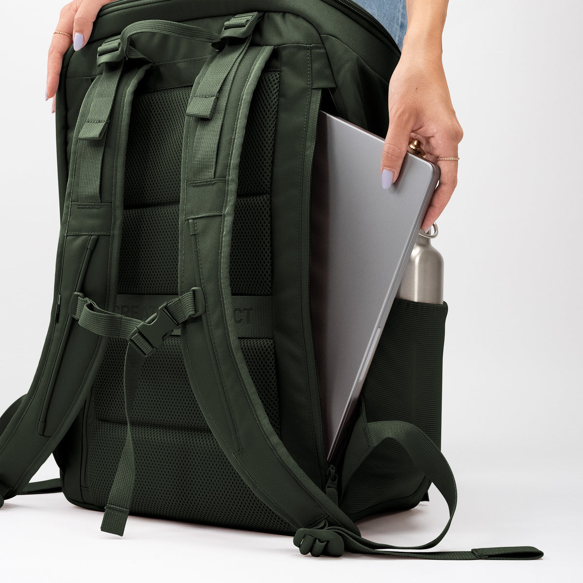 PRO PACK TRAVEL Rucksack in algae (Dunkelgrün mit Graustich), in den eine Frau Laptop und Wasserflasche verstaut.