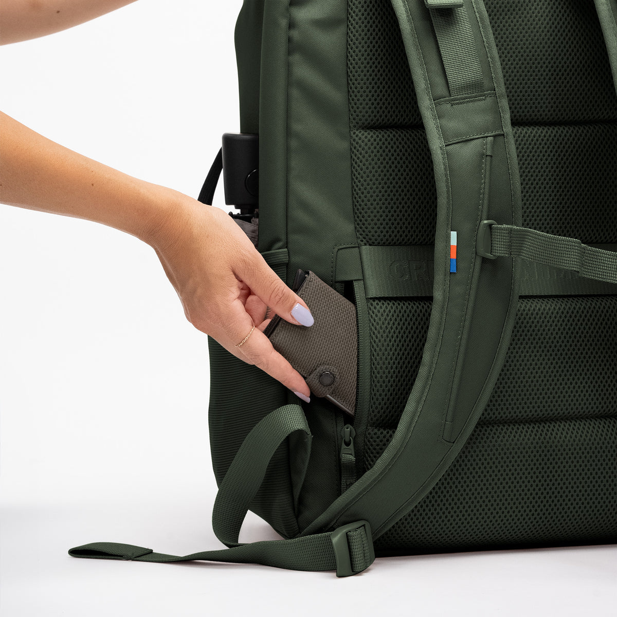 PRO PACK TRAVEL Rucksack in algae (Dunkelgrün mit Graustich) als Detailaufnahme einer Frau, die eine Brieftasche in eine Tasche steckt.