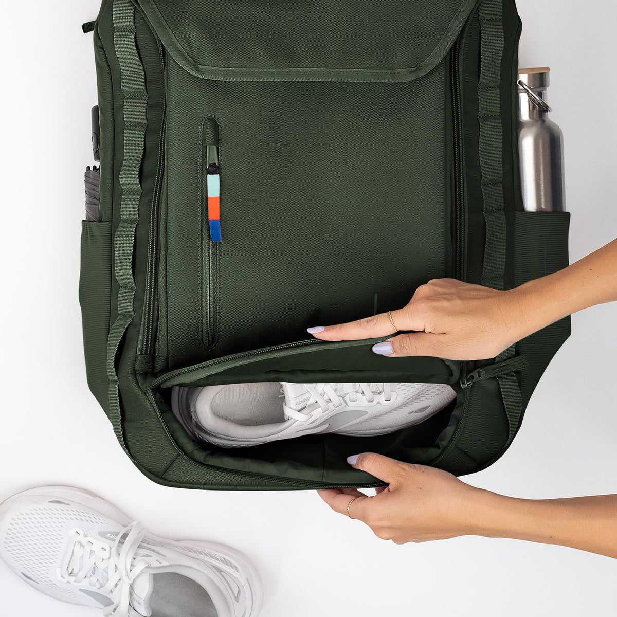 PRO PACK TRAVEL Rucksack in algae (Dunkelgrün mit Graustich), Frau öffnet Fach mit weißem Sneaker.