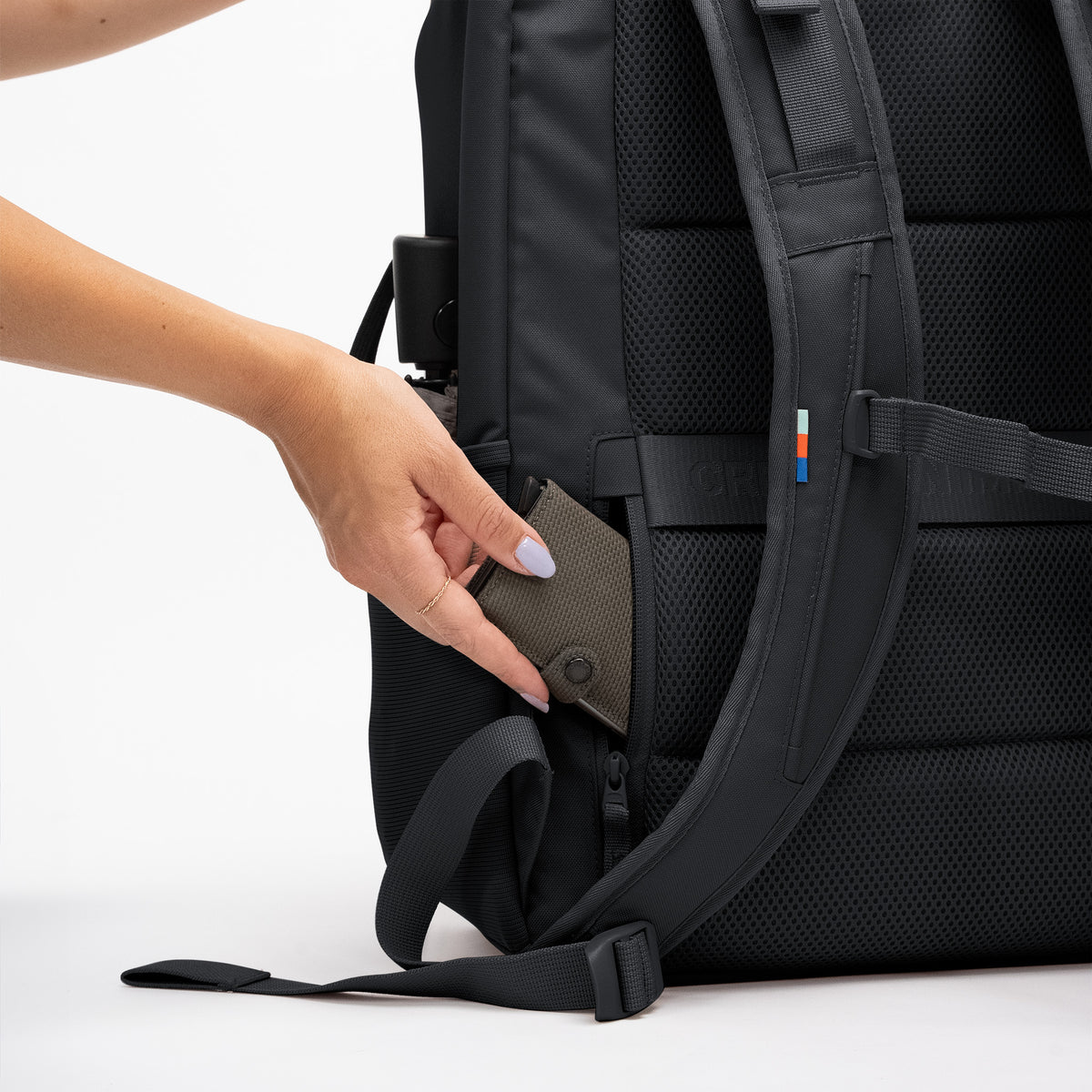 PRO PACK TRAVEL Rucksack in black (Schwarz) Detailaufnahme der Seitentasche, aus der eine Frau ein Accessoire entnimmt.