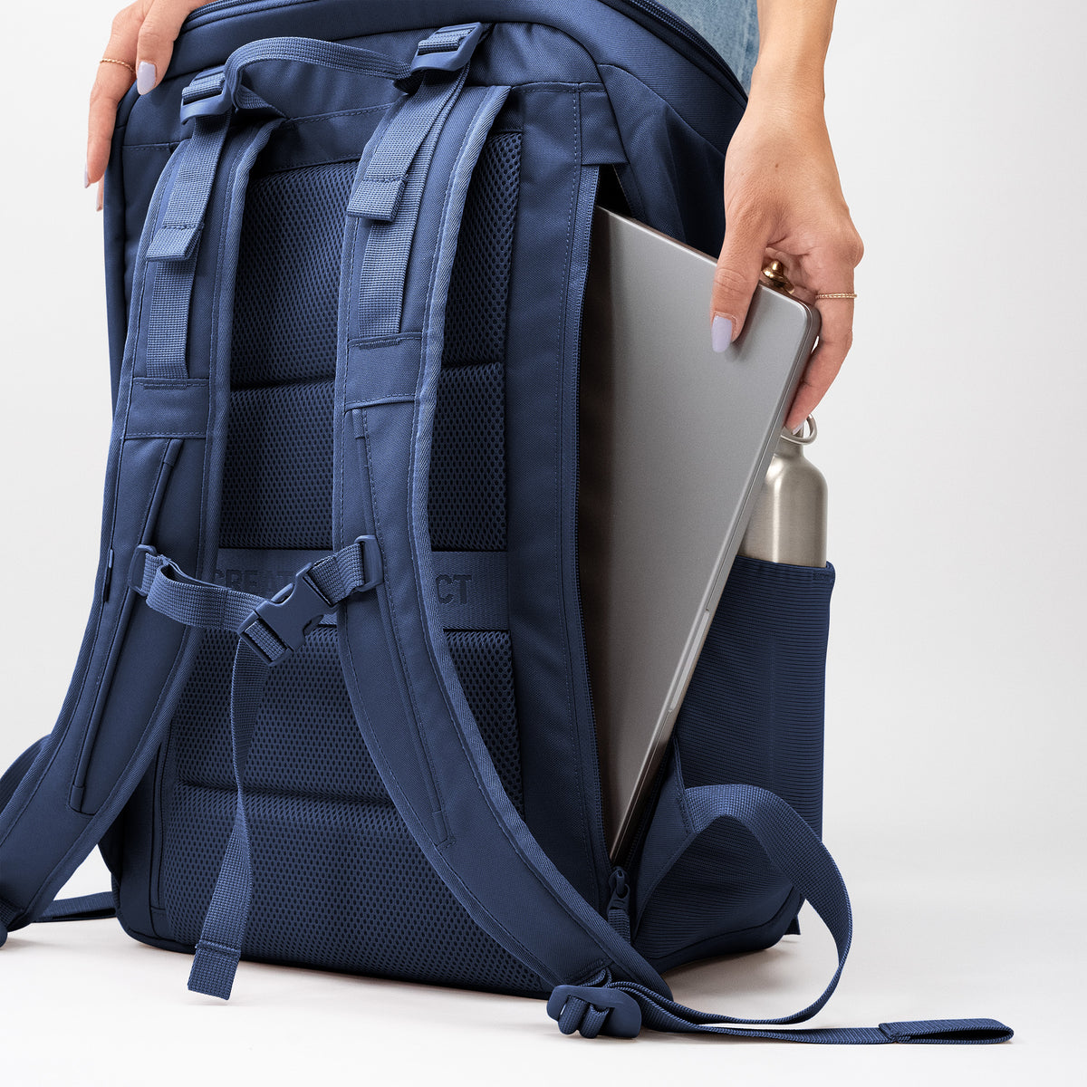 PRO PACK TRAVEL Rucksack, in den eine Frau einen Laptop und eine Trinkflasche steckt.