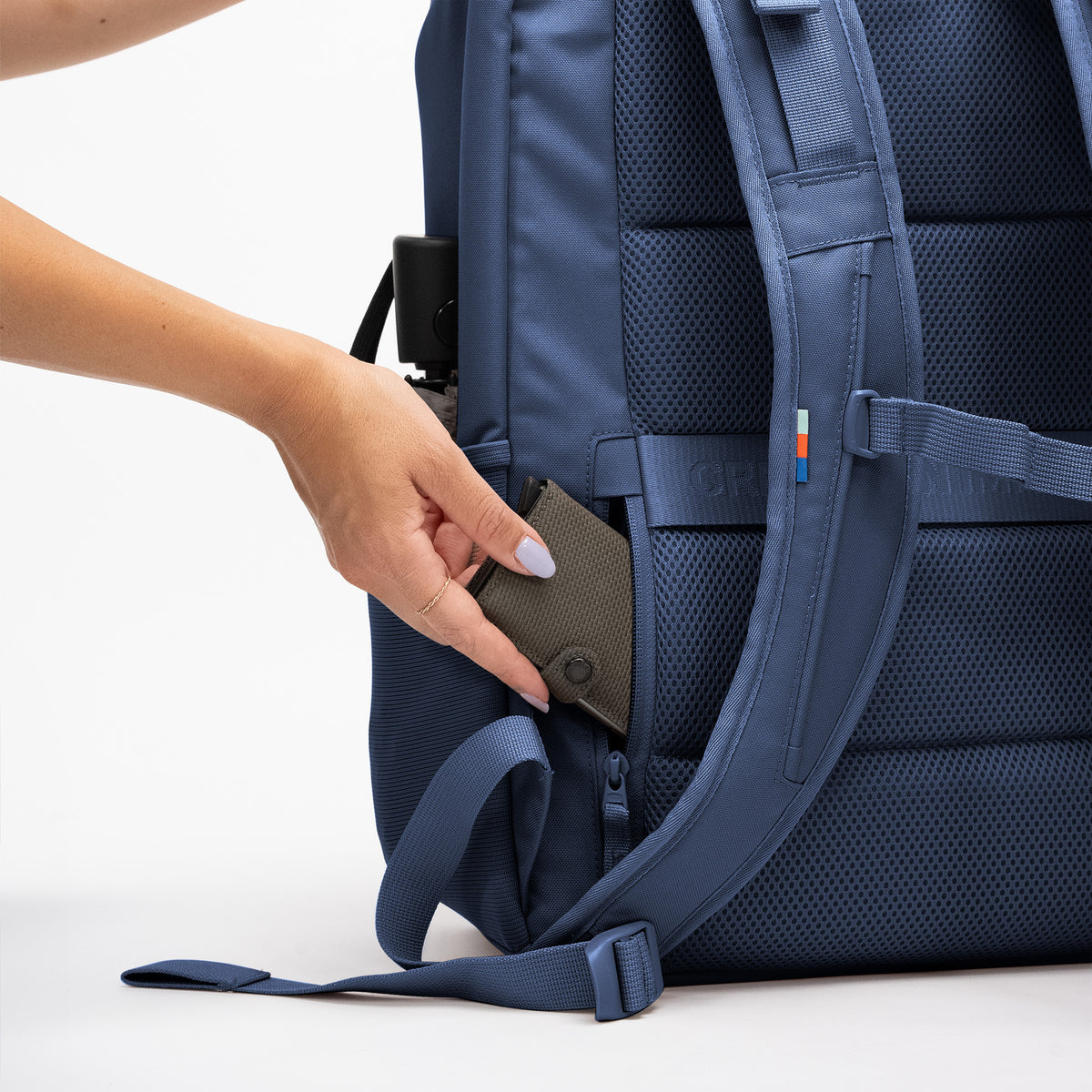 PRO PACK TRAVEL Rucksack, in dessen Seitentasche eine Frau ein Portemonnaie steckt.